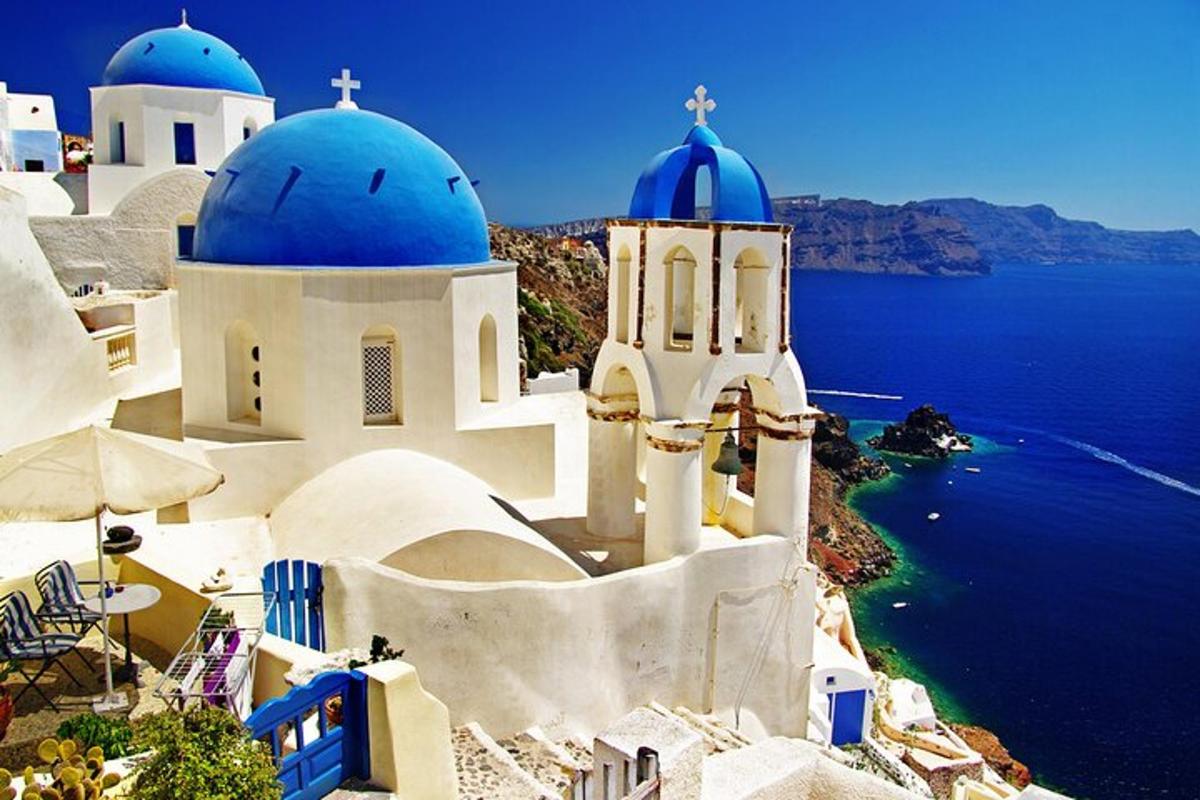 Un grupo de edificios blancos con cúpulas azules y el océano.