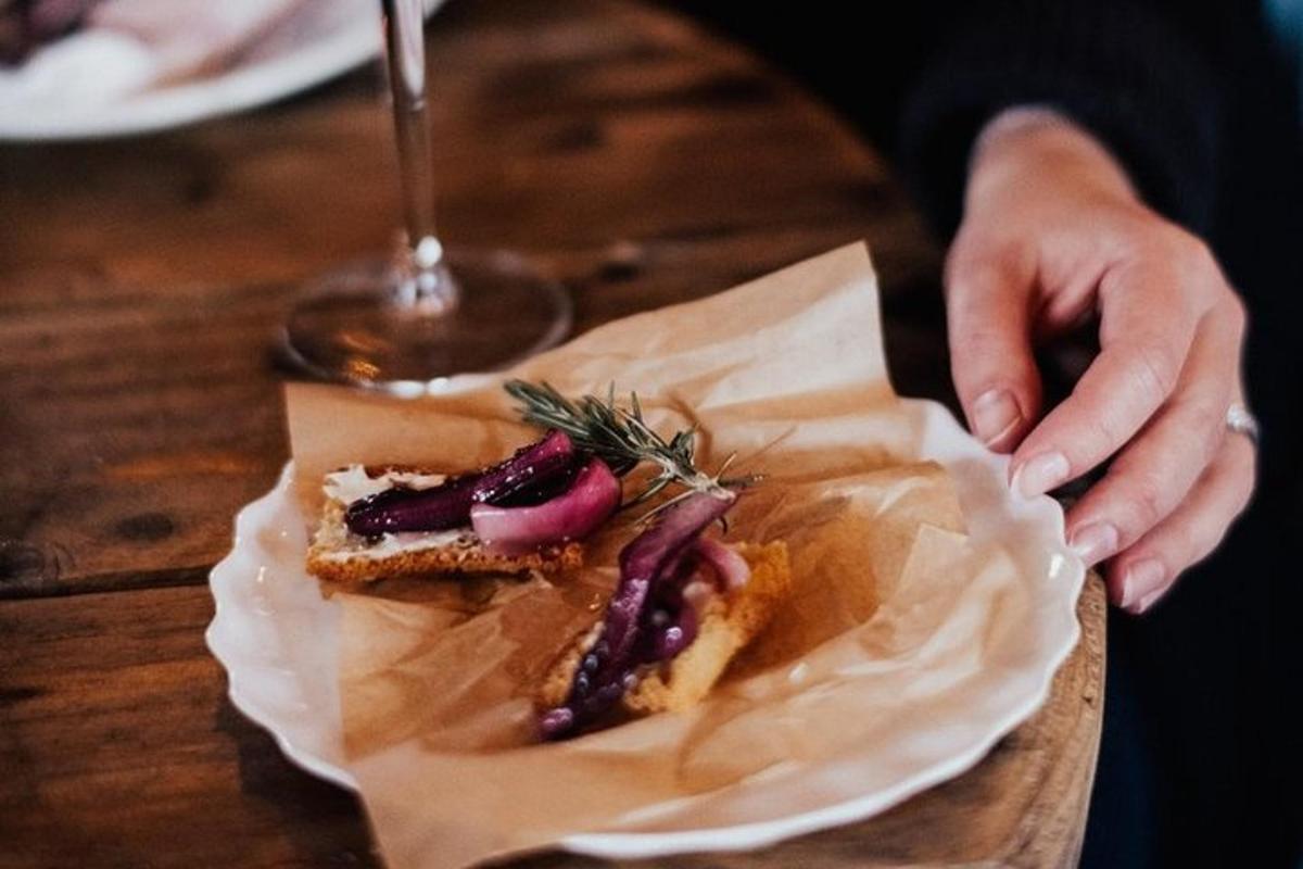 una persona sosteniendo un trozo de comida sobre una mesa de madera
