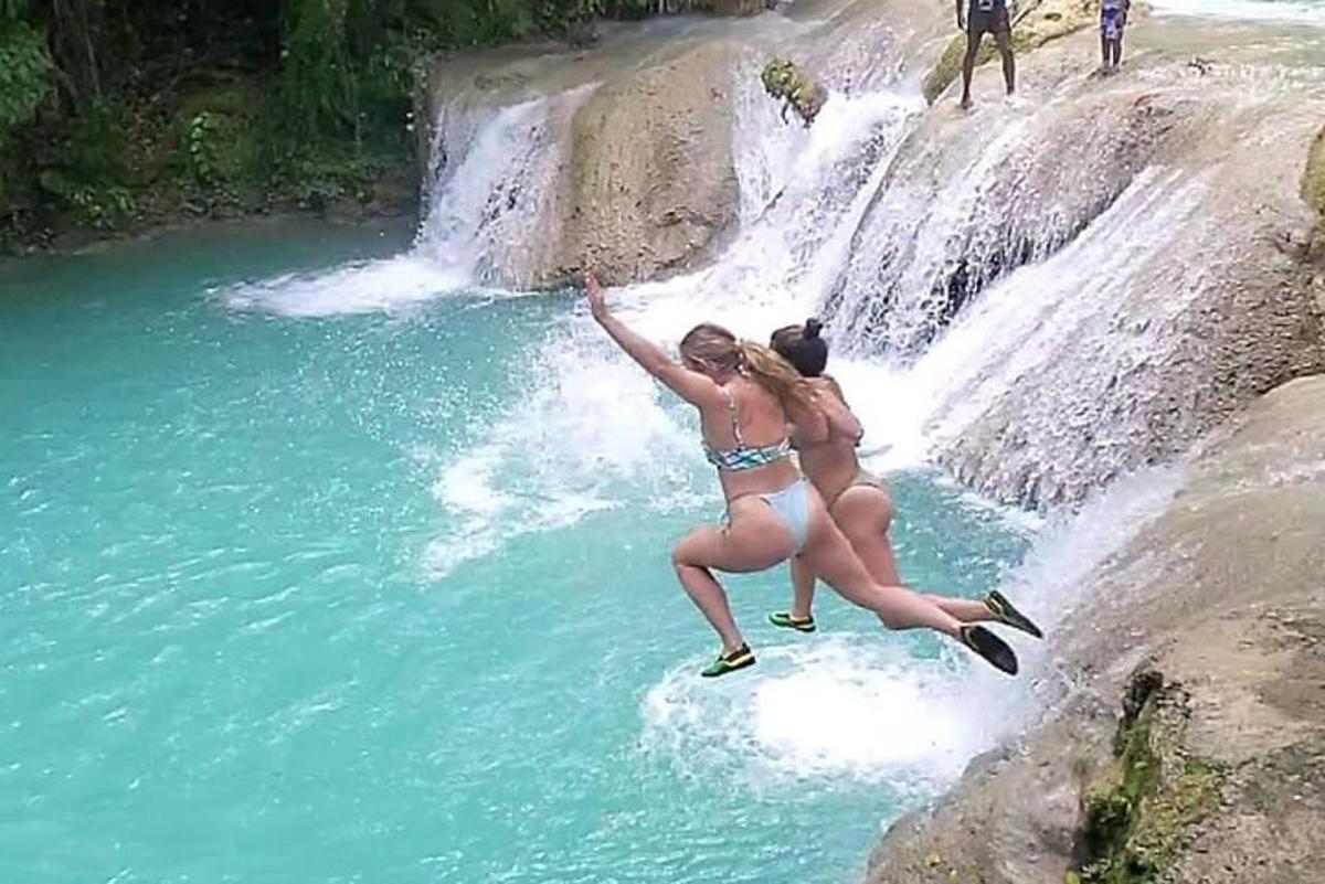 twee vrouwen in badpakken springen in een waterval