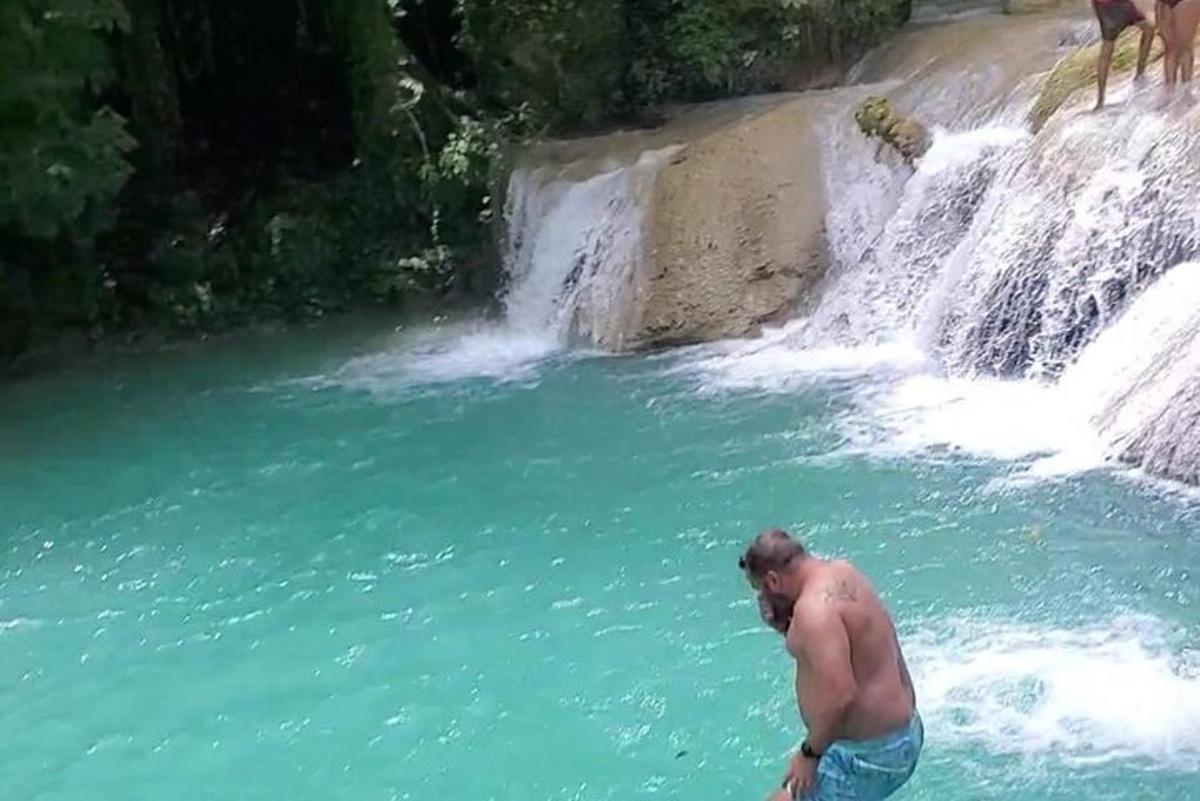 een man die in het water staat naast een waterval