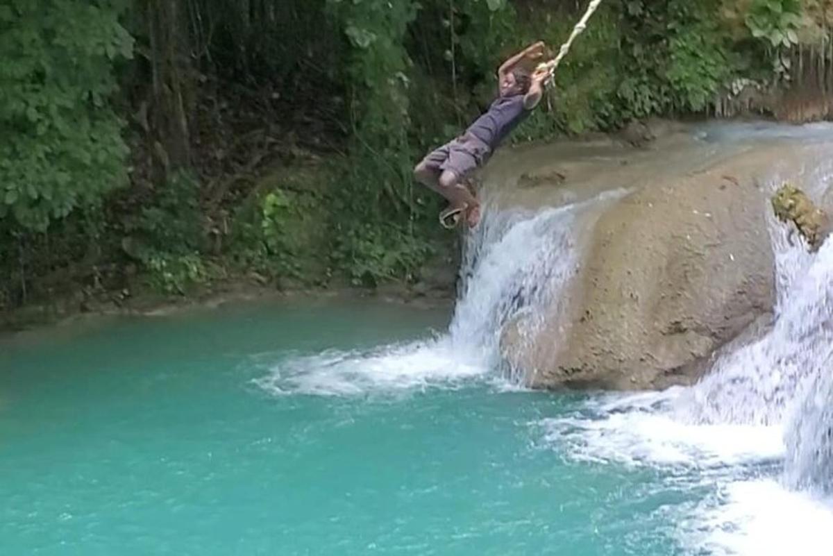 un uomo sta saltando da una roccia in un fiume