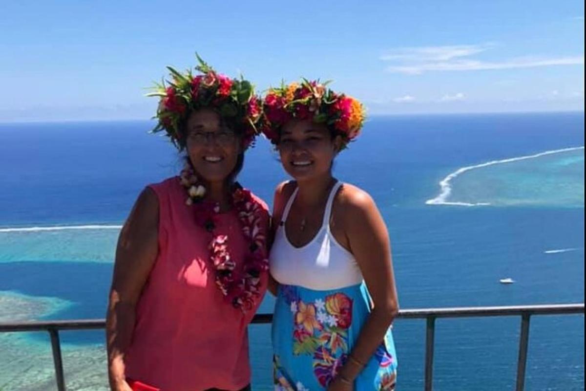 two women with flowers on their heads standing on a balcony