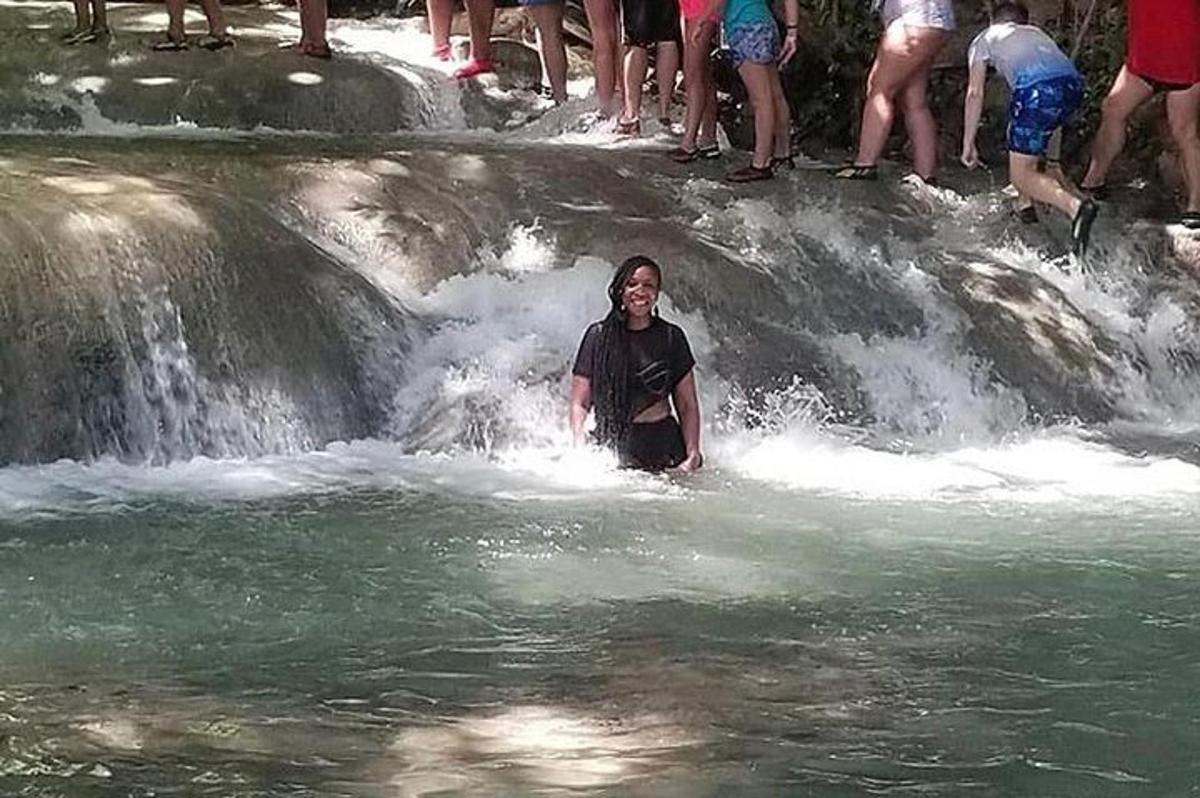 un uomo in piedi nell'acqua di fronte a una cascata
