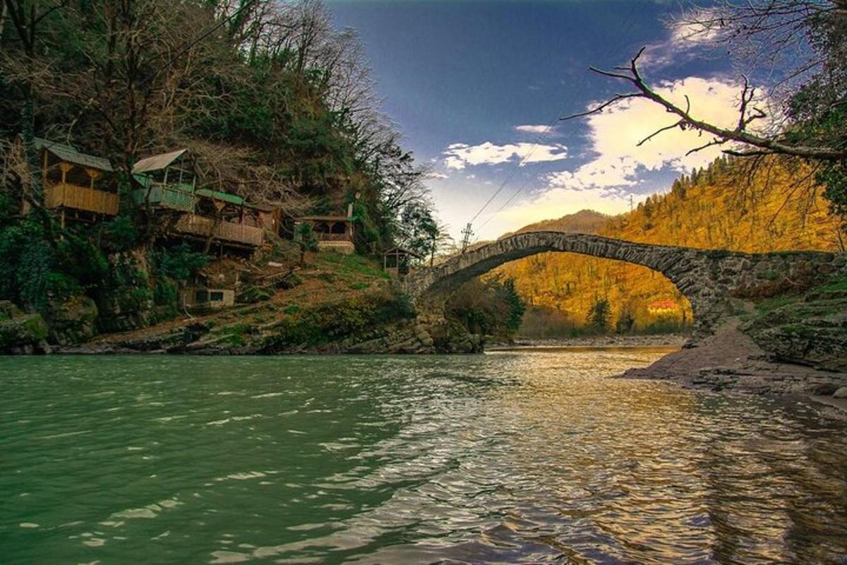 a bridge over a river next to a mountain
