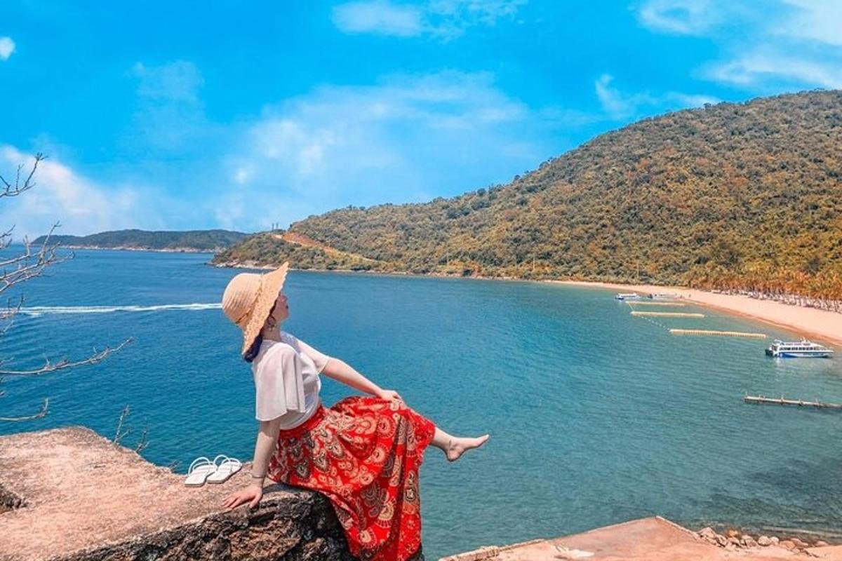 una dona asseguda en una roca amb vistes a una platja