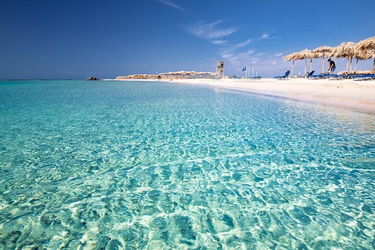 una playa con agua cristalina y sombrillas de paja