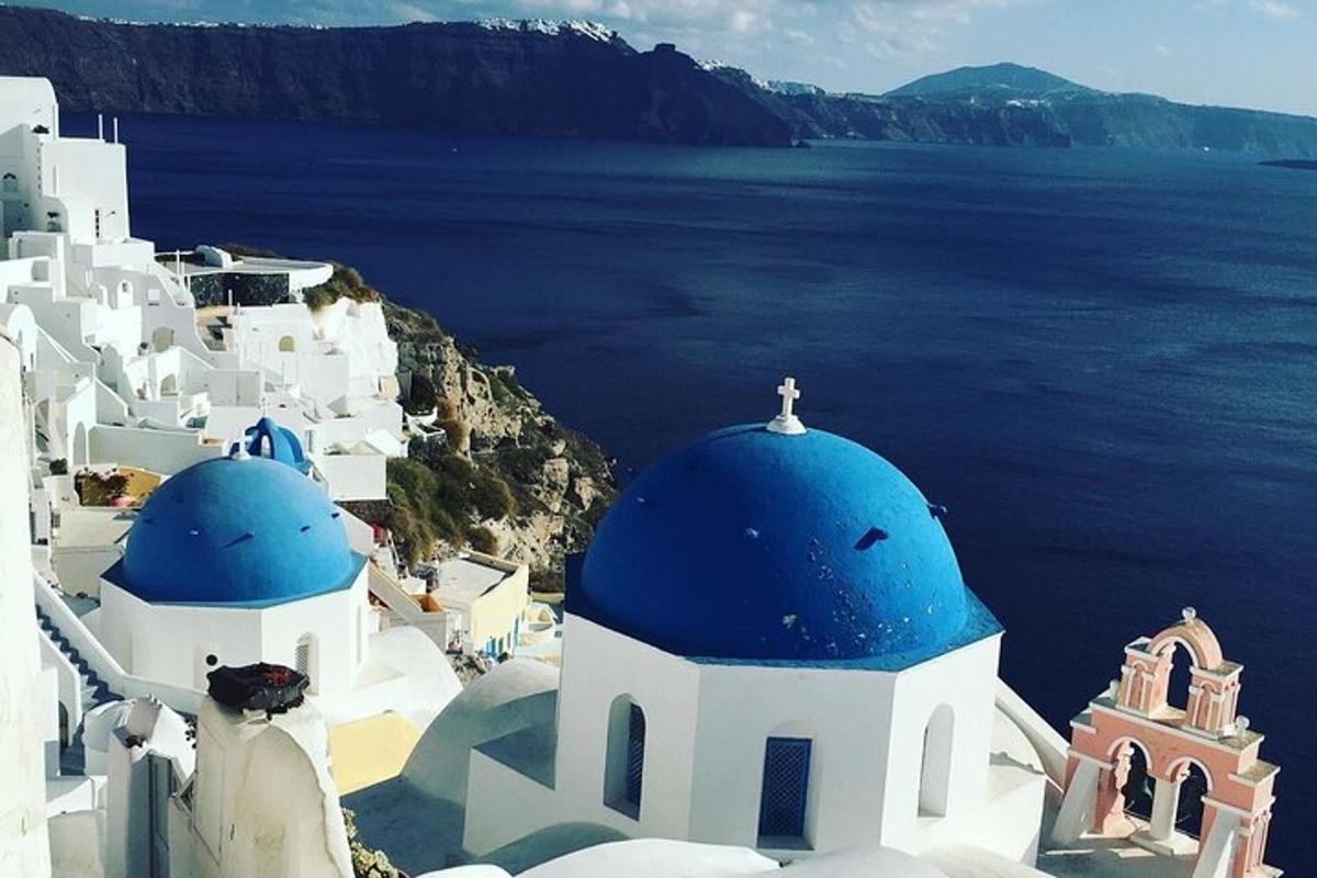 a group of white buildings with blue domes and the ocean