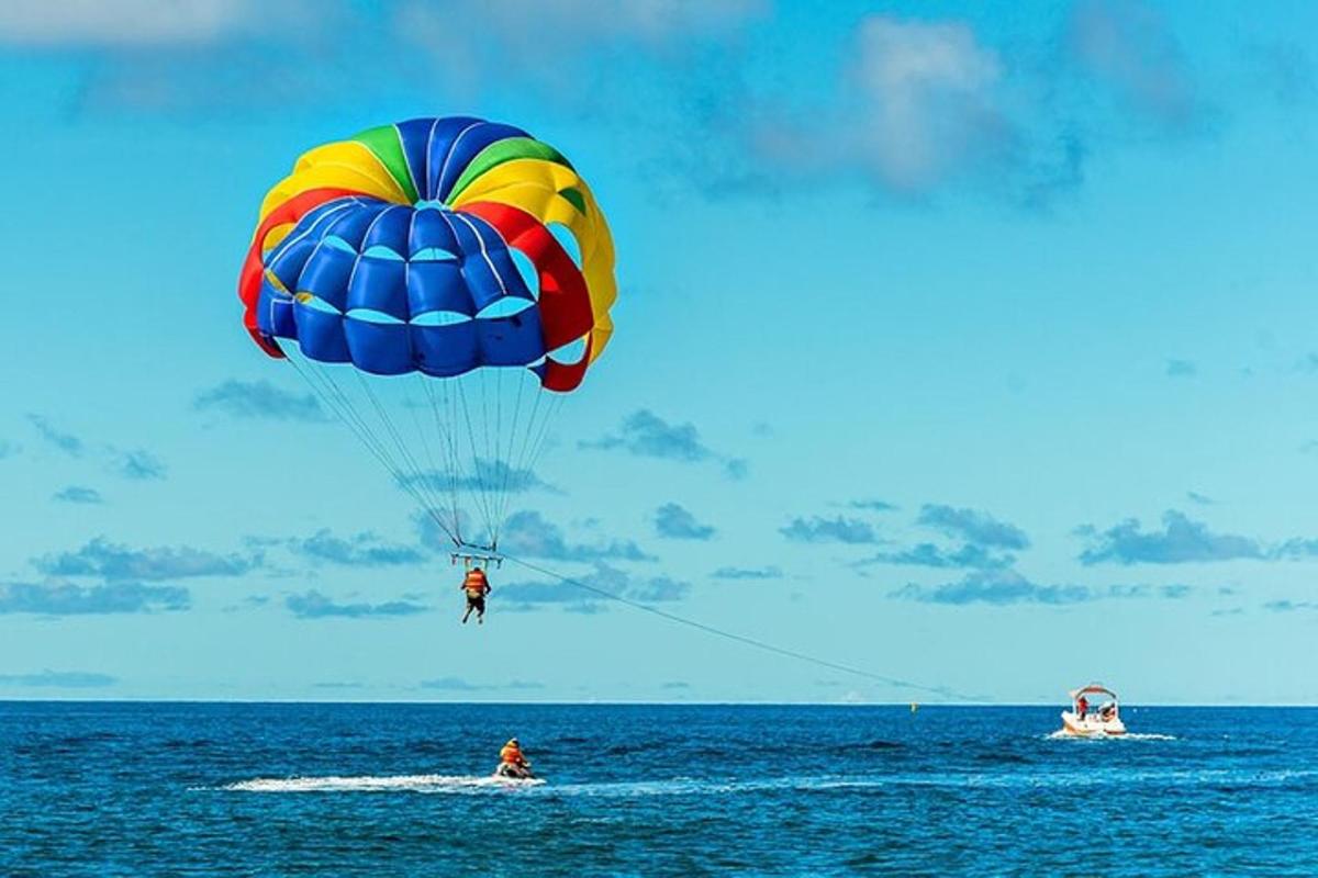 osoba letící s padákem nad oceánem