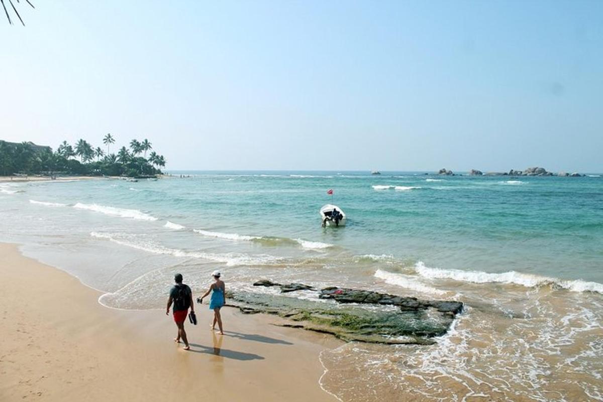 two people walking on the beach near the ocean