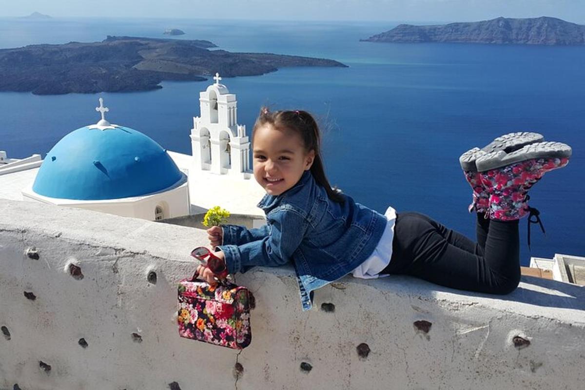 seorang gadis kecil duduk di dinding sambil memegang tumbuhan