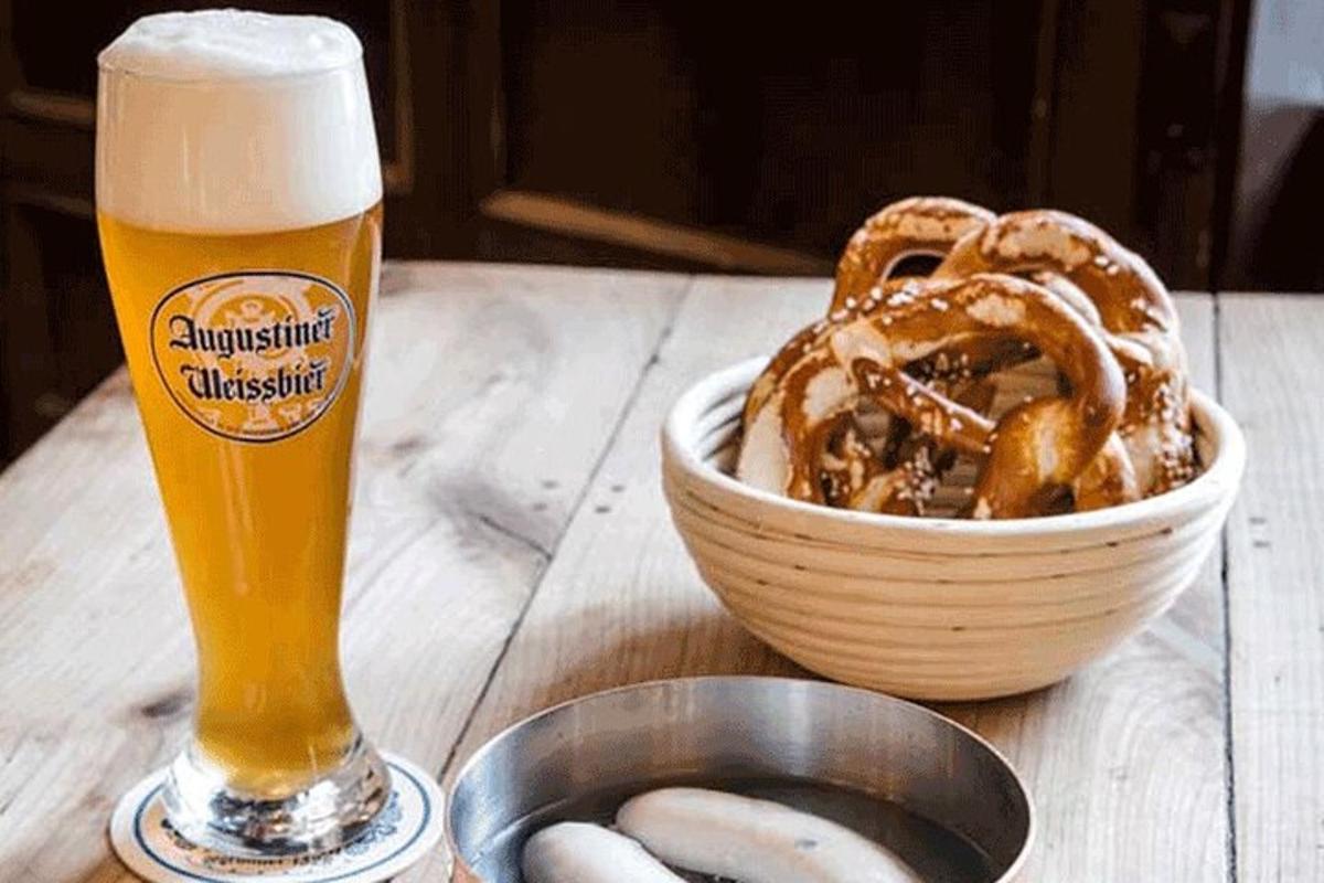 ein Glas Bier neben einer Schüssel Brezeln