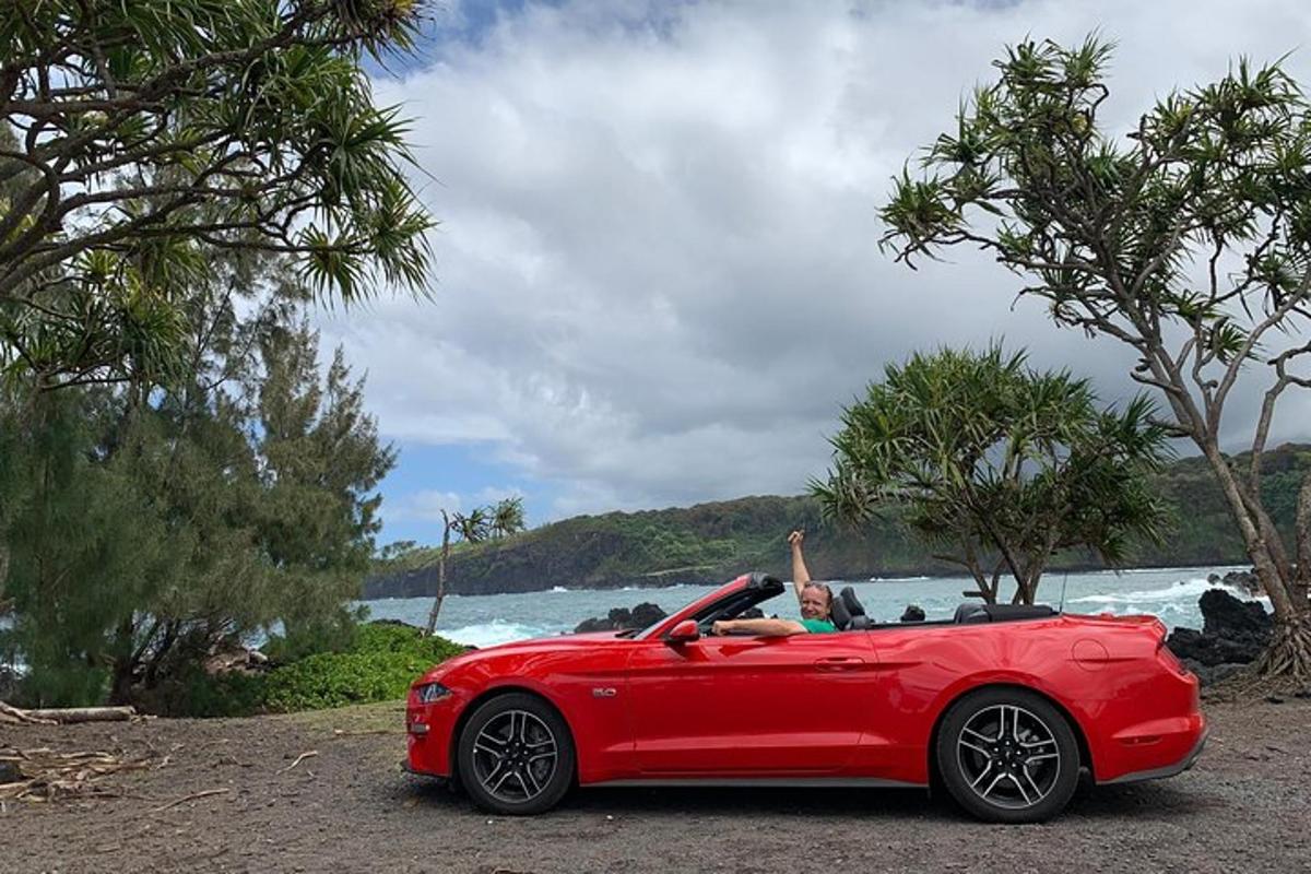 Un coche rojo aparcado al lado de una playa