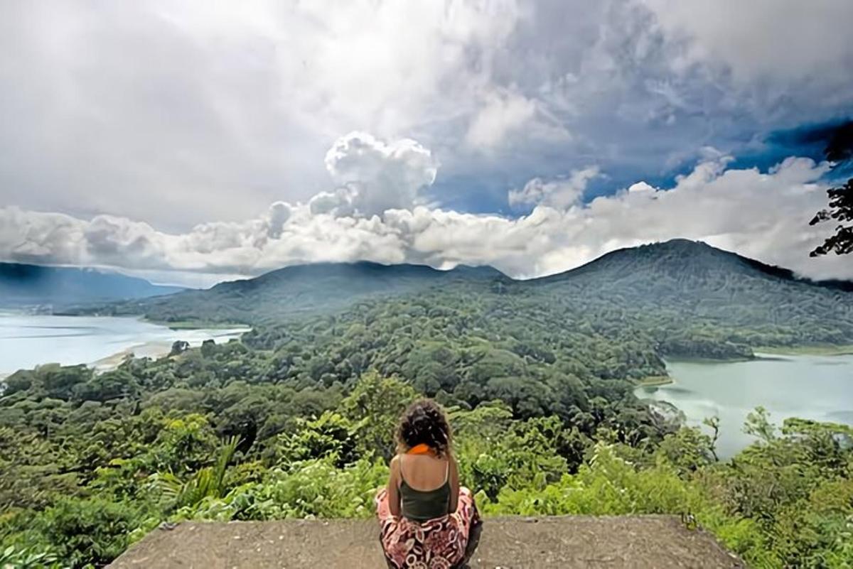 una donna seduta in cima a una roccia che guarda un lago