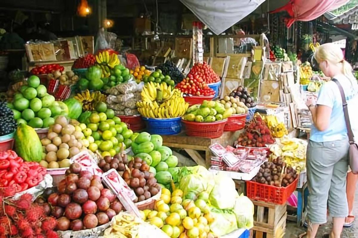 una donna in piedi in un mercato con frutta e verdura