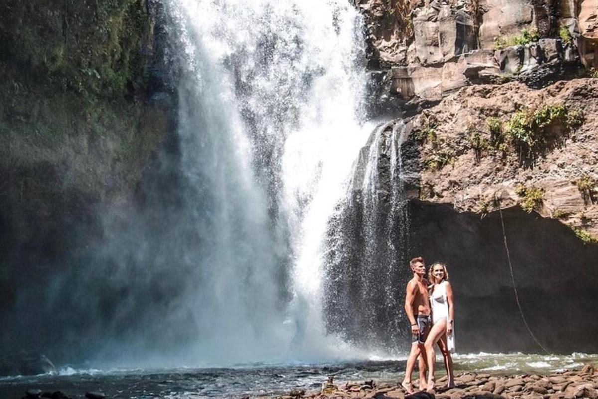 a man and woman standing in front of a waterfall