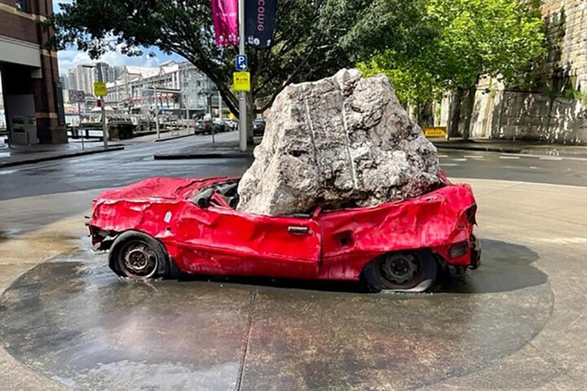 sebuah kereta merah dengan batu besar di tepi jalan