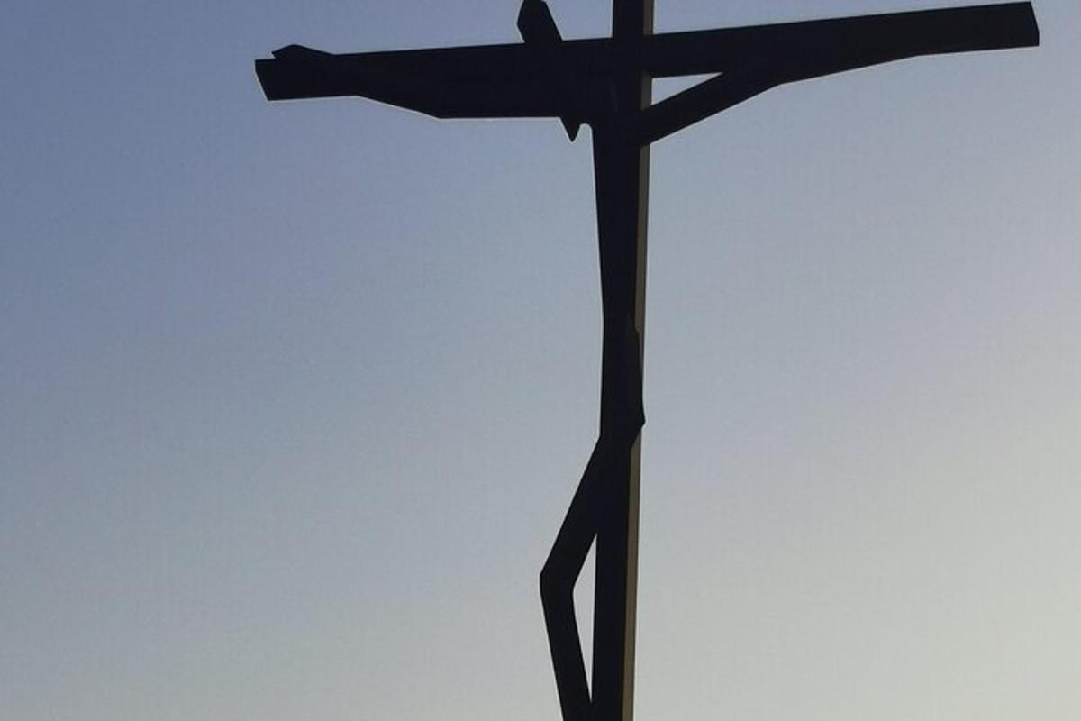 una cruz de madera negra sobre un fondo blanco