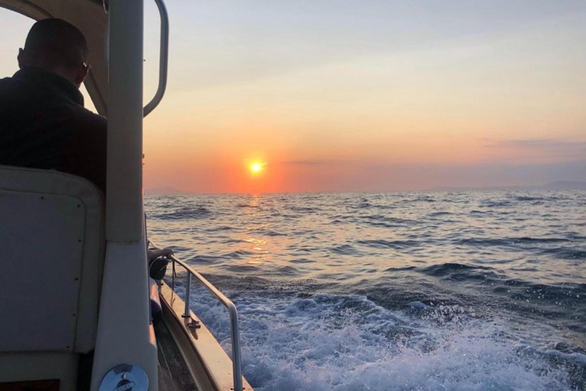 egy férfi ül egy csónakban, és nézi a naplementét