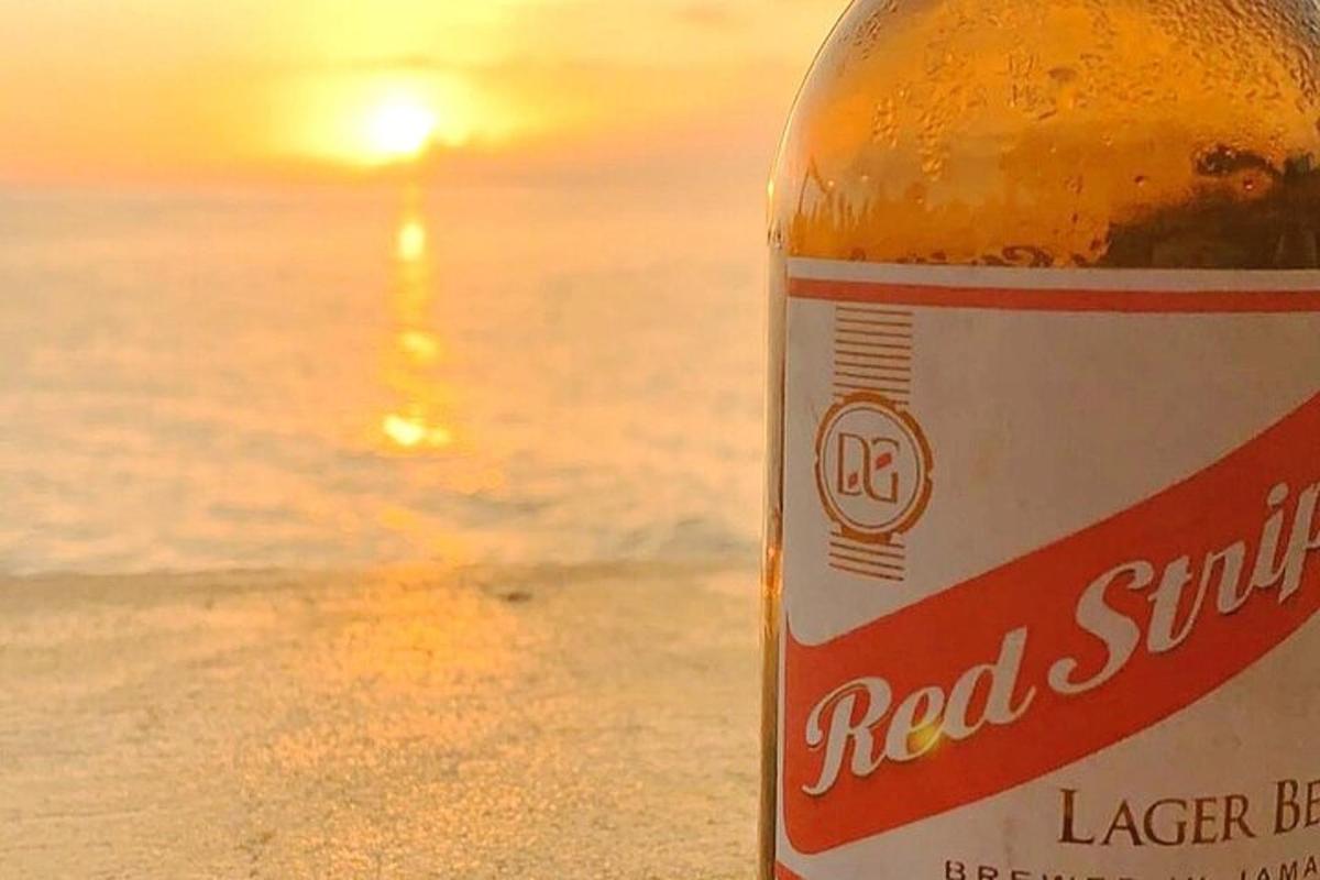 夕日を眺めながらビーチに座りながらビールのボトル