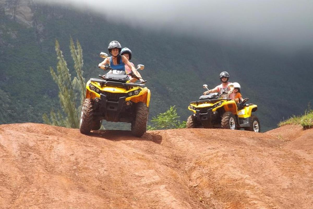 two people riding on atvs on a dirt hill