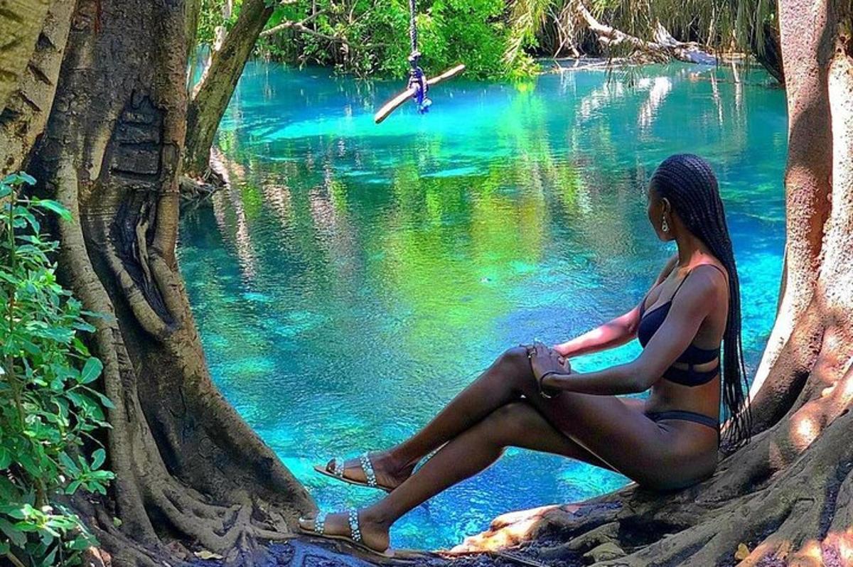 seorang wanita berbaju mandi duduk di tepi sungai