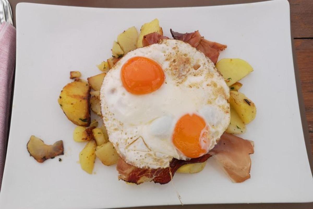 a fried egg on top of potatoes on a white plate