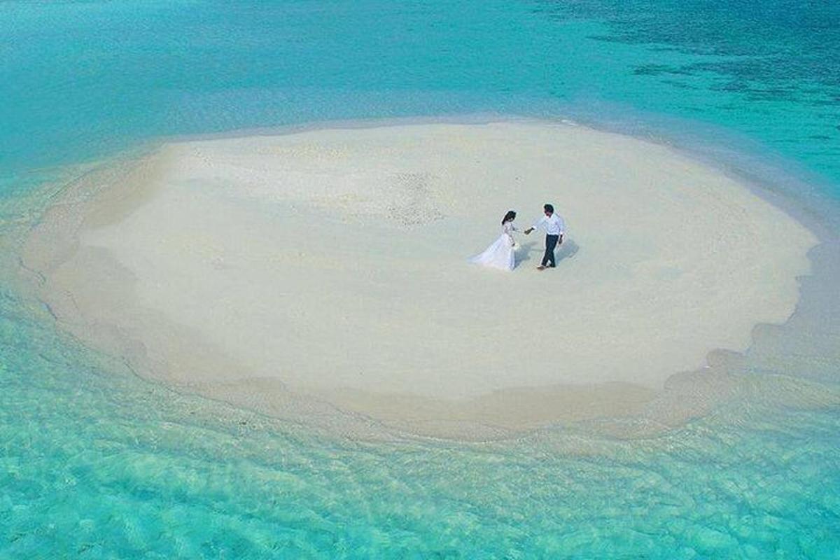 una sposa e uno sposo in piedi su un'isola nell'oceano