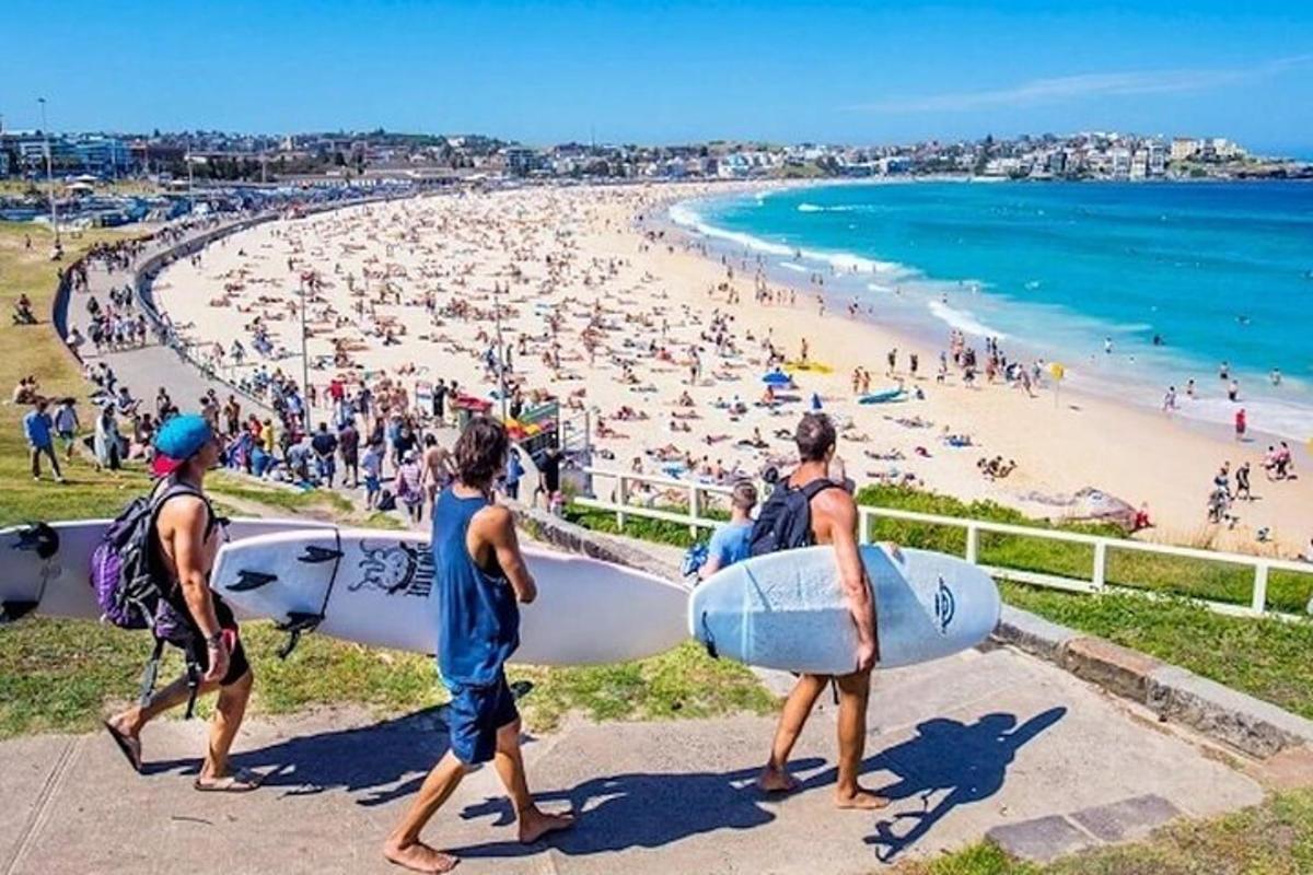 um grupo de pessoas caminhando na praia com pranchas de surfe
