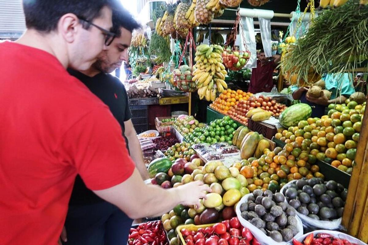 due uomini in piedi in un mercato con frutta e verdura