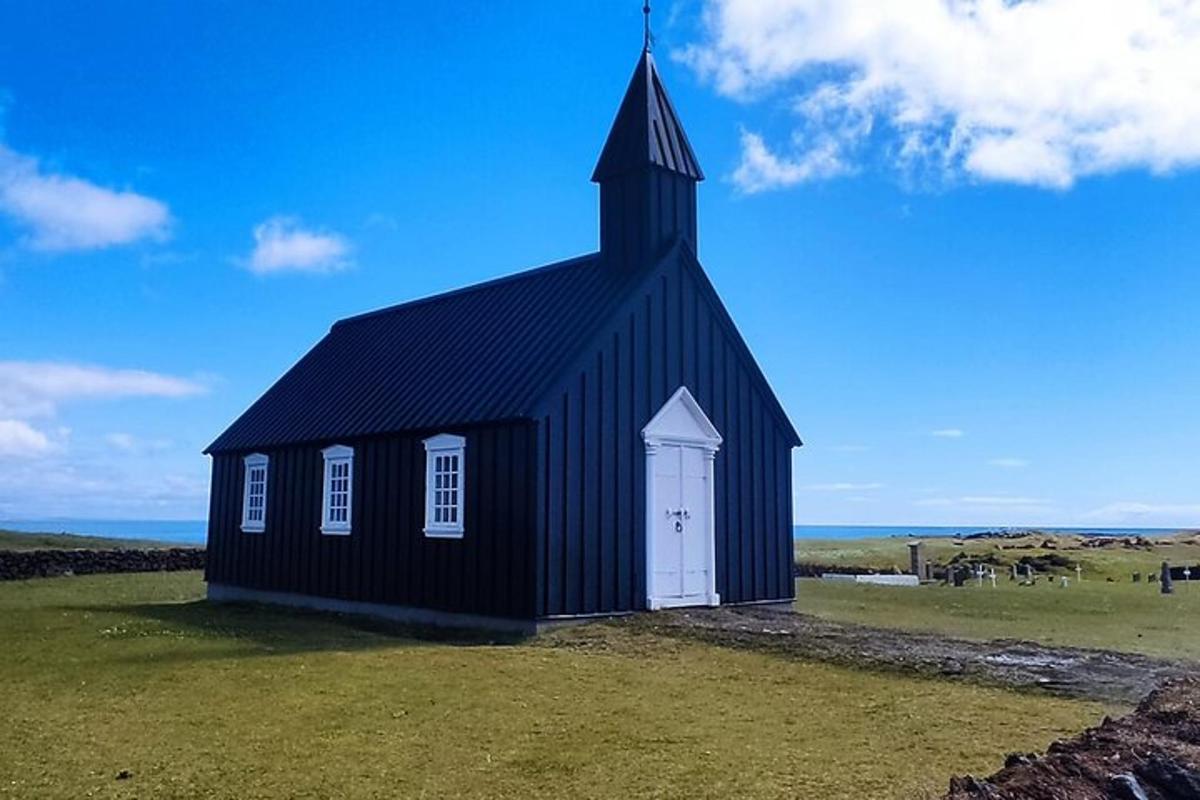 eine schwarze Kirche mit einem Kirchturm auf einem Feld