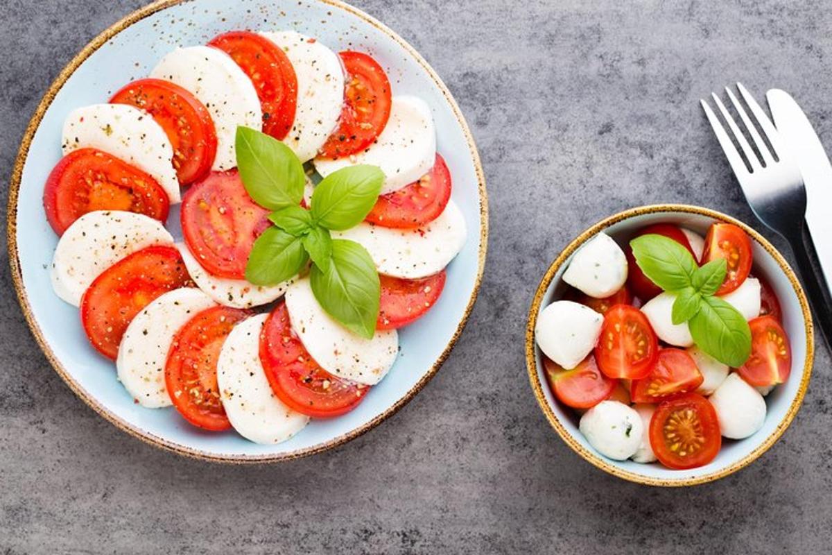 Dos platos de comida con tomates y un bol con un tenedor.