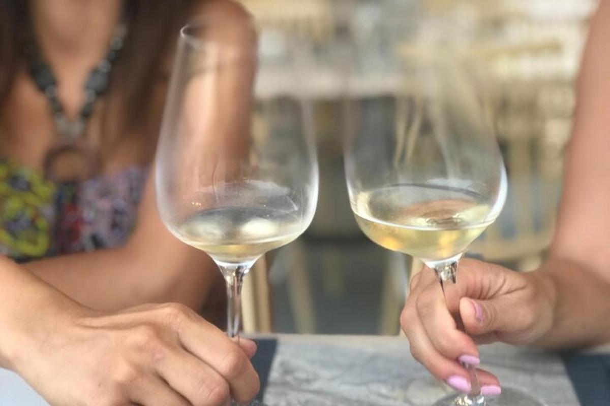 Δύο άτομα κρατούν ποτήρια λευκού κρασιού