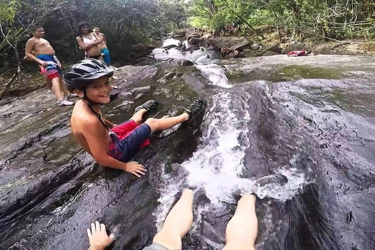 a young boy sitting on a rock in a river