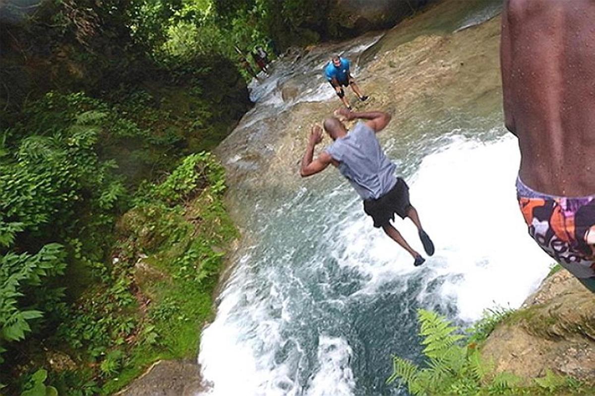 a man is jumping into a river in a waterfall