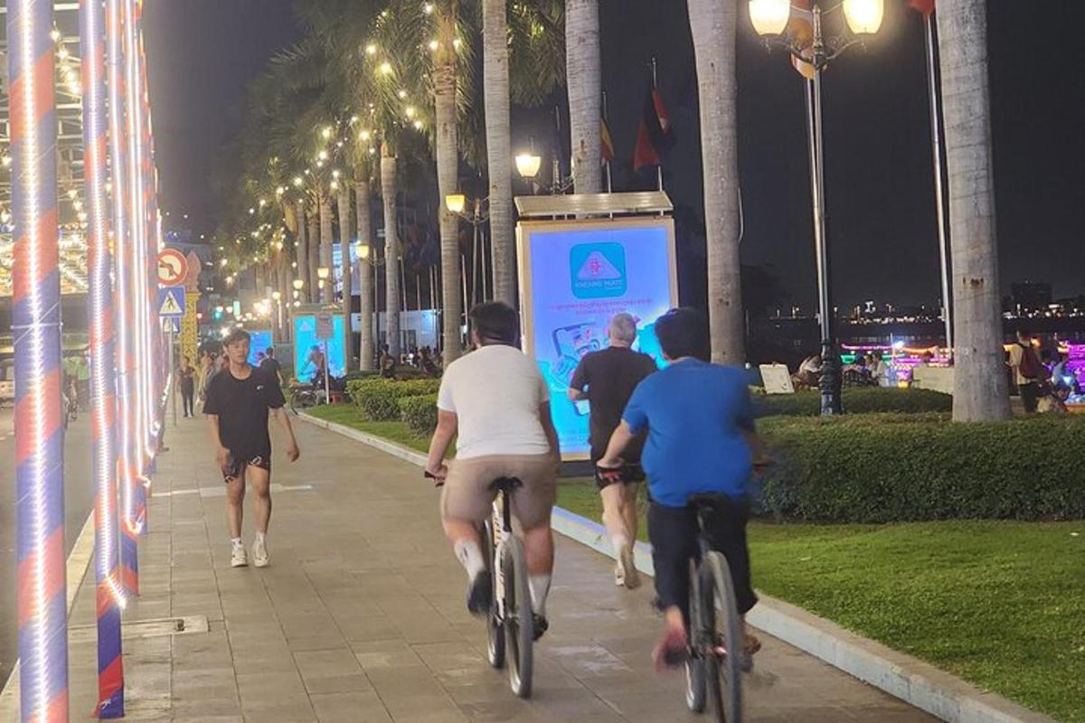 a group of people riding bikes down a sidewalk at night