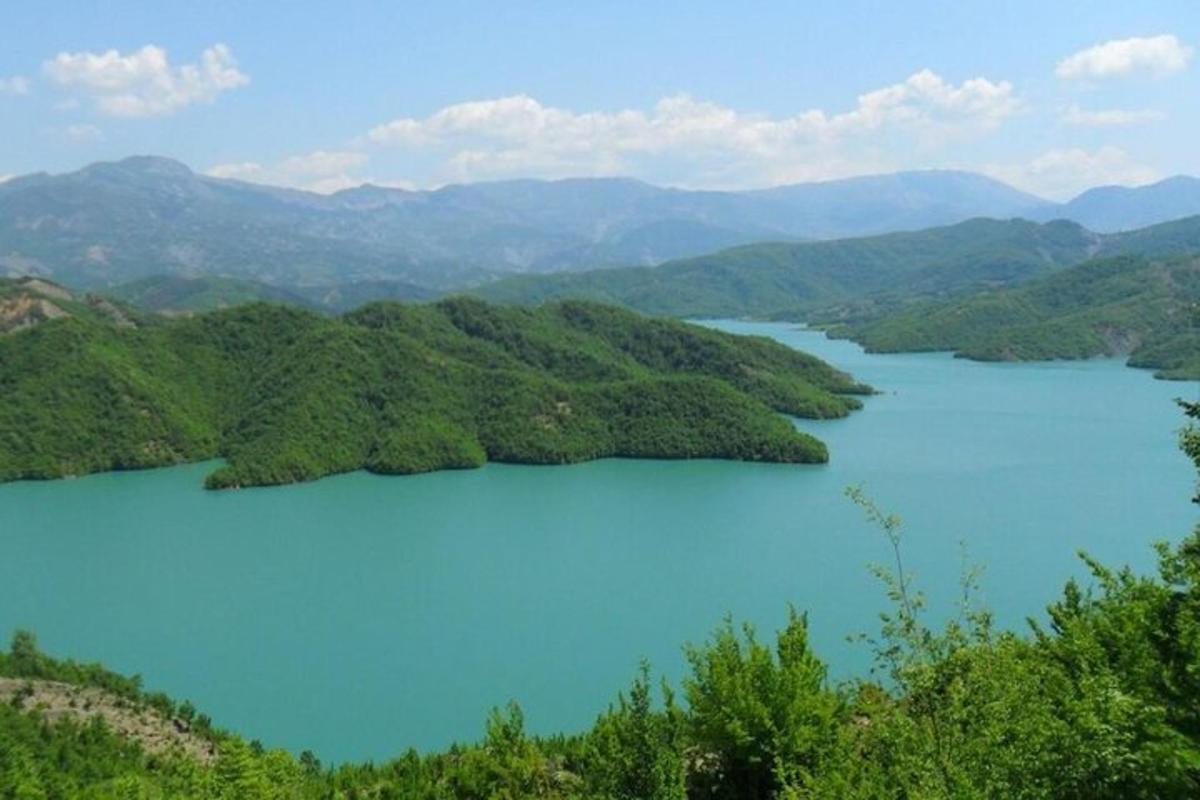 Una vista de un lago azul con colinas verdes.