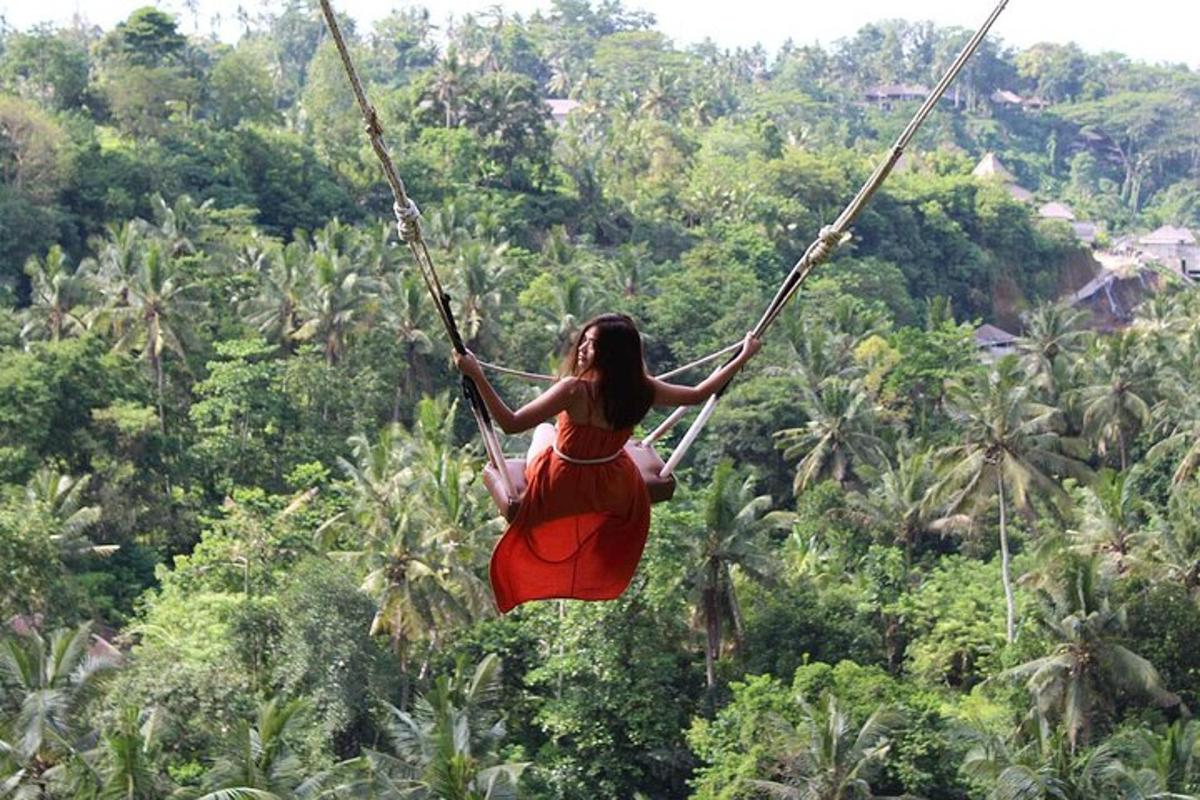 una donna con un vestito rosso che si dondola su un'altalena di corda