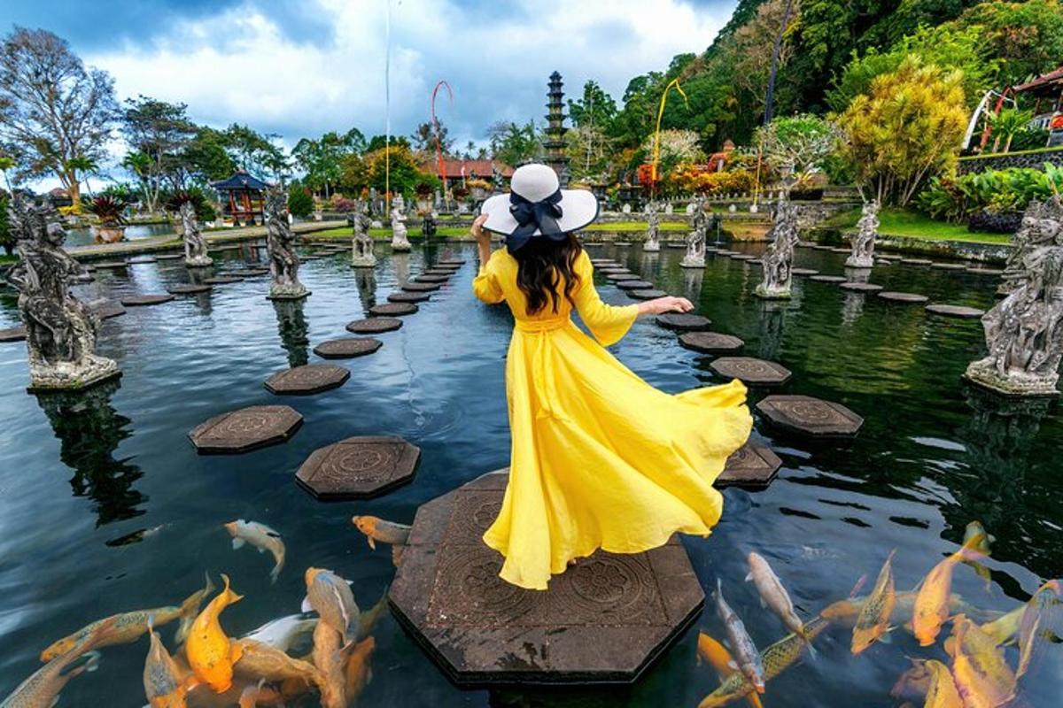seorang wanita bergaun kuning berdiri di kolam berisi ikan