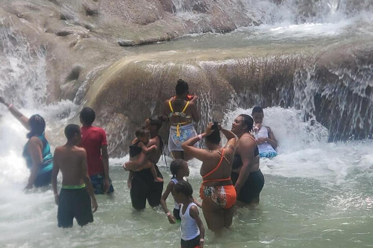um grupo de pessoas em pé na água perto de uma cachoeira