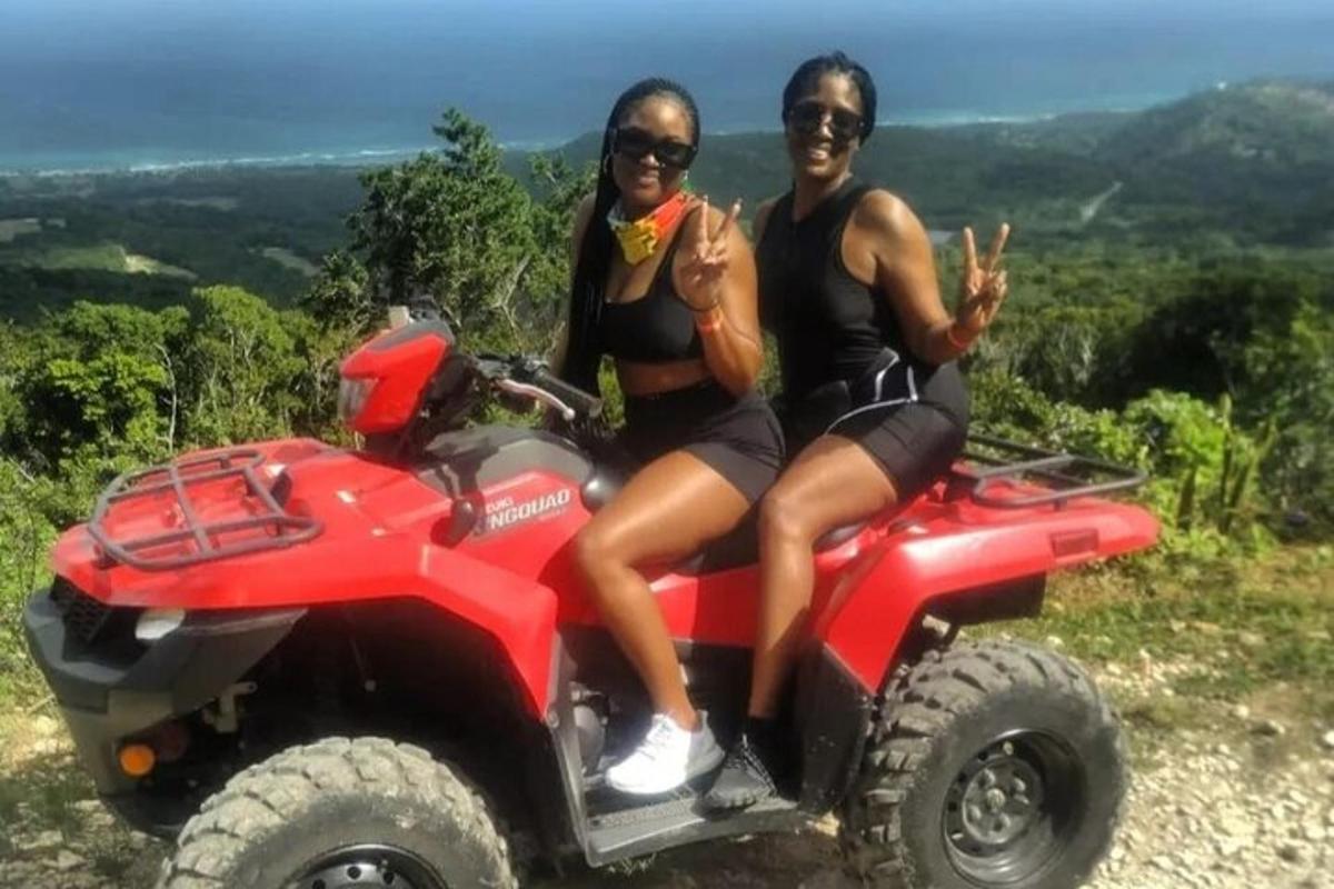 two women sitting on a fourwheeler while posing for a picture