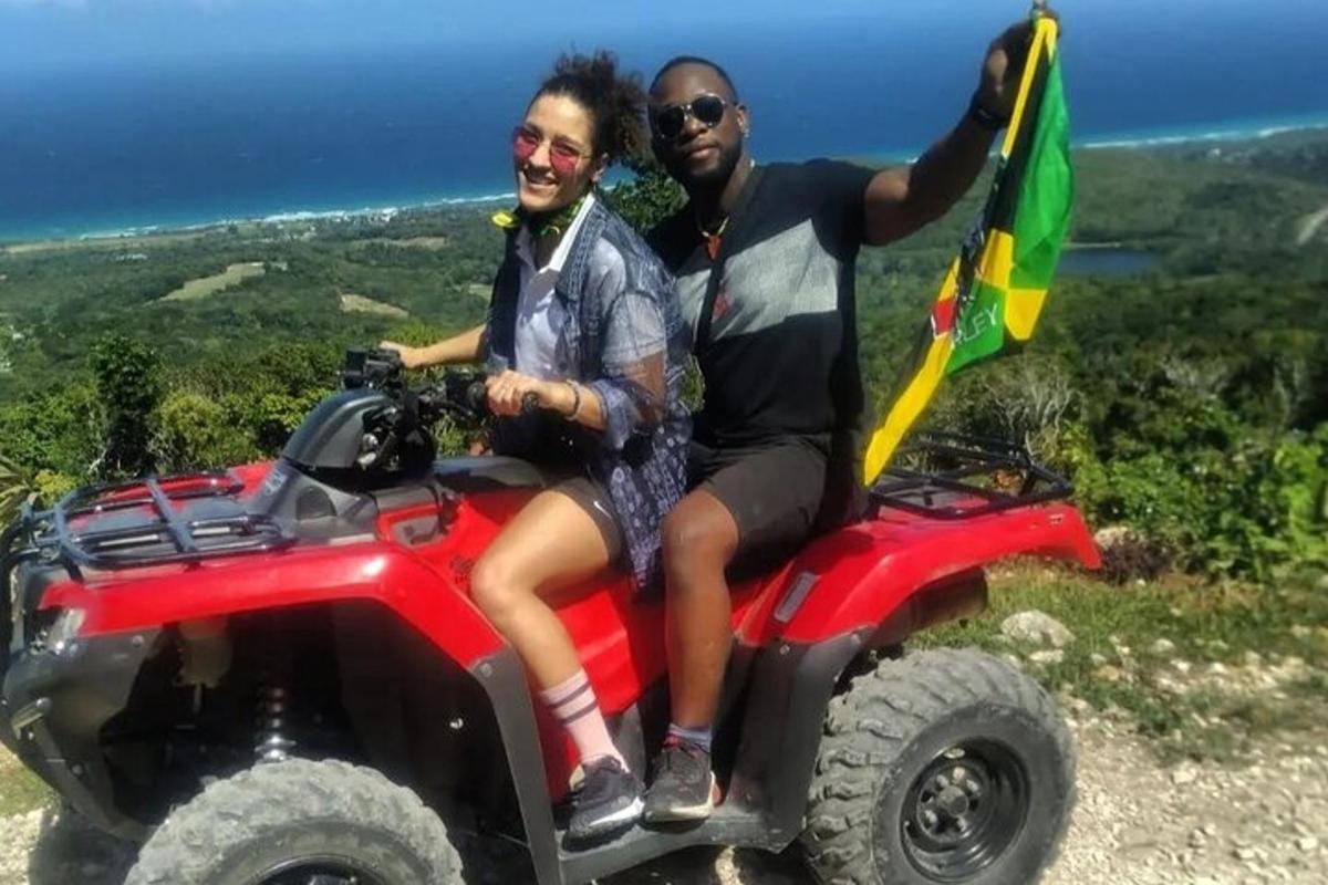 two people sitting on a fourwheeler with a flag