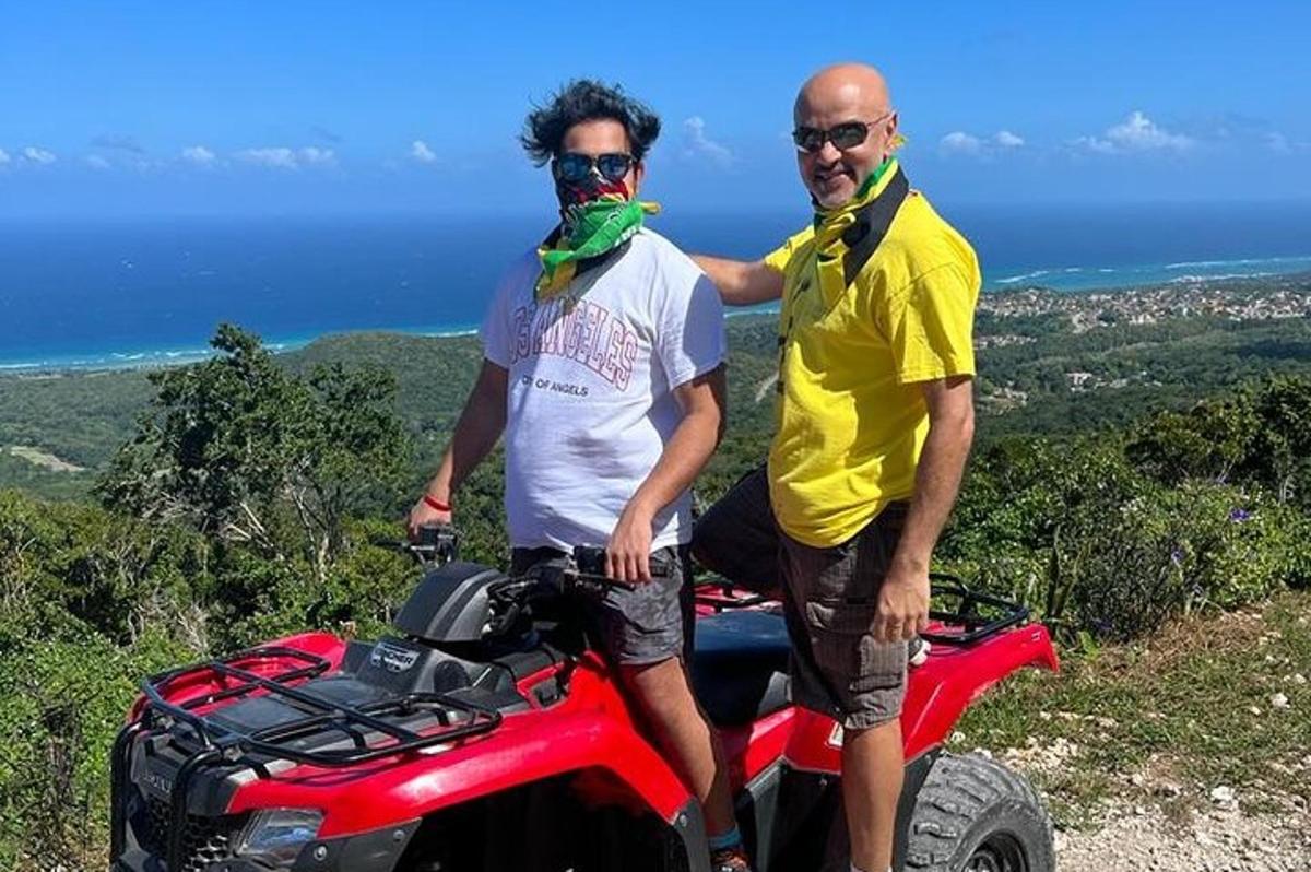 two men are standing next to a atv