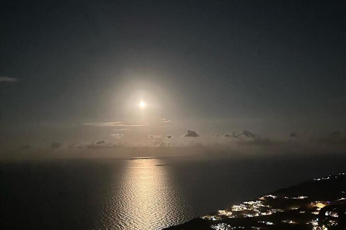 μια πανσέληνος που ανατέλλει πάνω από τον ωκεανό τη νύχτα