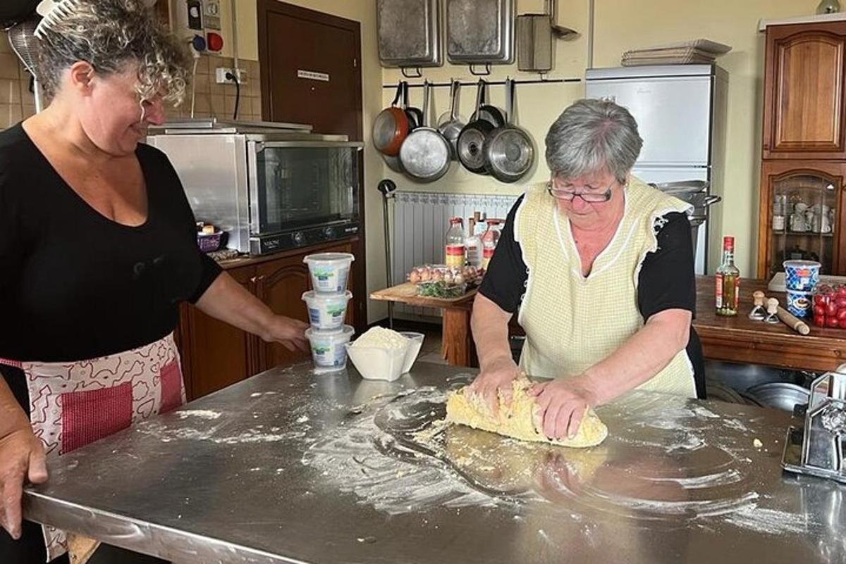 two women standing in a kitchen making a dough
