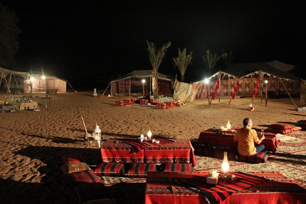 seseorang duduk di pantai pada malam hari dengan lilin di atas meja