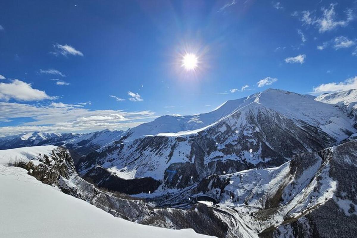 a snow covered mountain with the sun in the sky