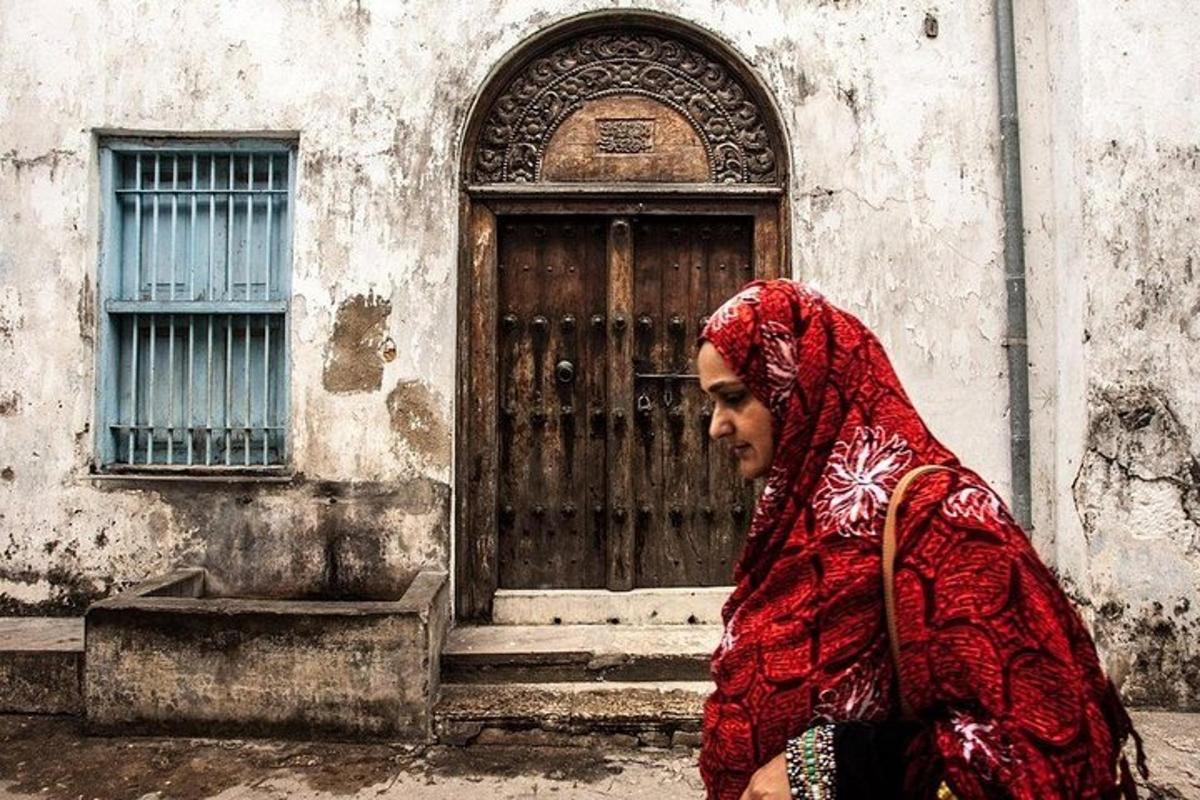 a woman walking down a street in front of a door