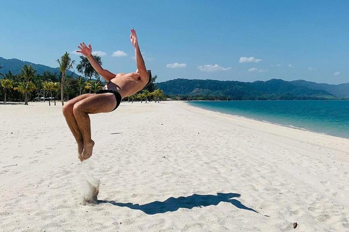 un uomo che salta in aria su una spiaggia