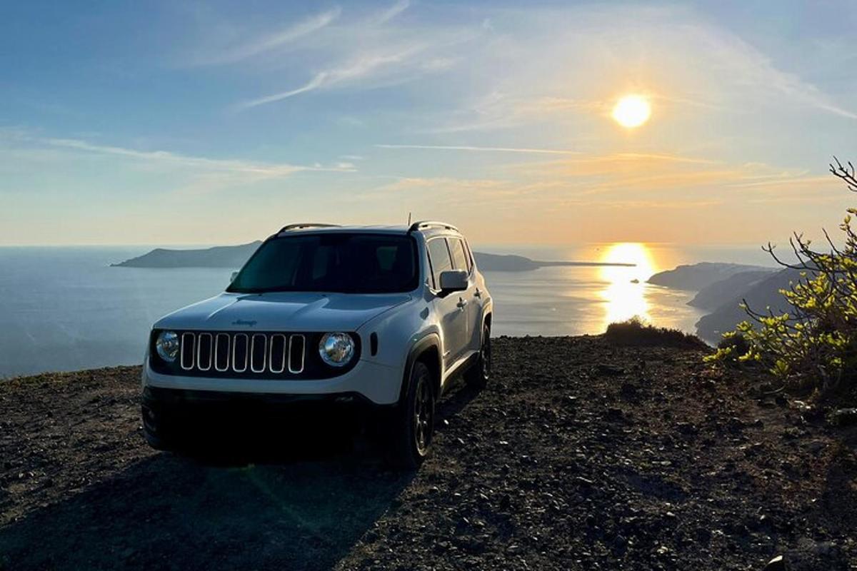 un jeep blanc aparcat al cim d'un turó amb la posta de sol