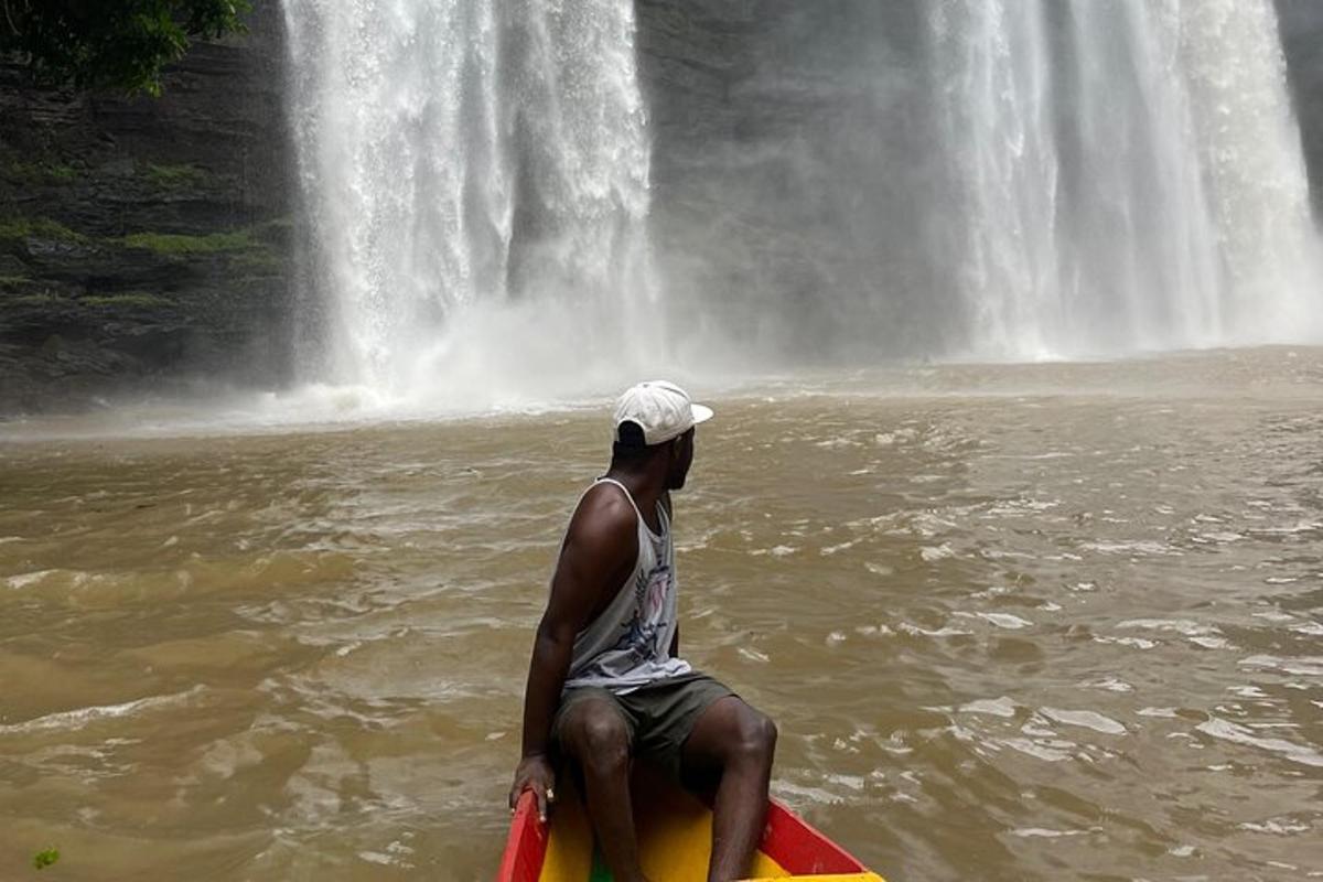 a man sitting on a kayak in the water near a waterfall